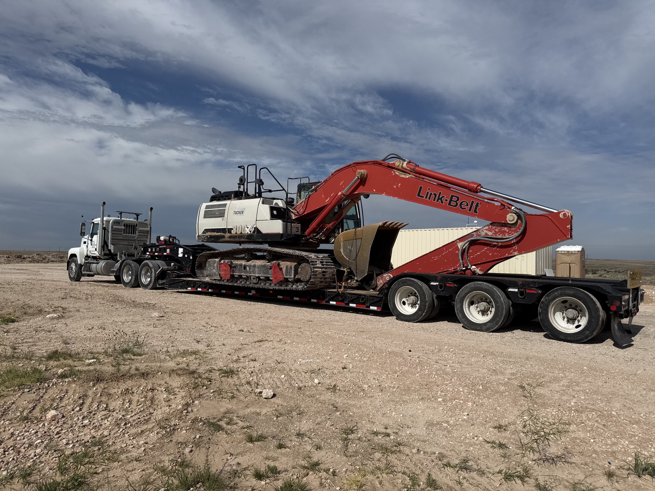 Heavy-haul truck transporting a large excavator at a Texas work site